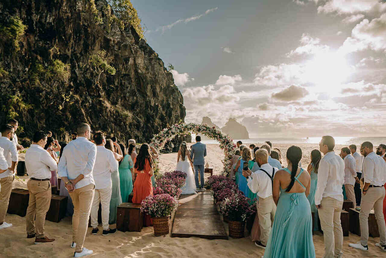 casamento pé na areia ao pôr-do-sol com altar florido