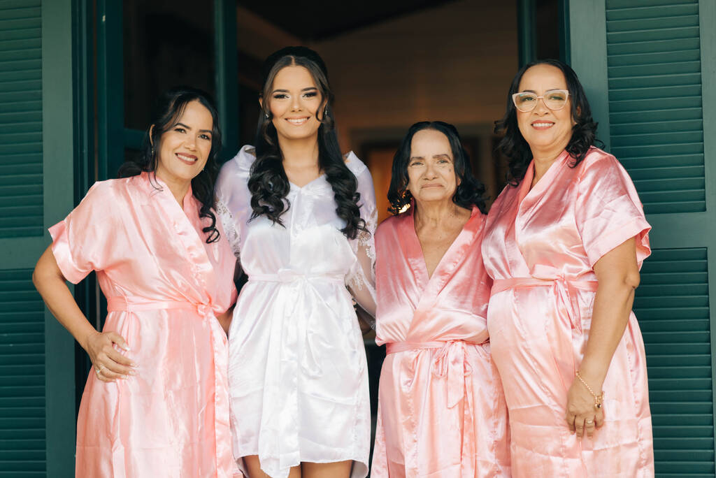 noiva com robe branco ao lado de mãe avó e madrinha com robe rosa