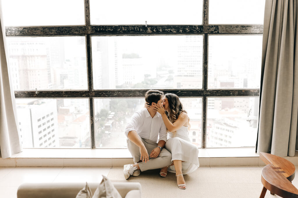 Casal se beijando na frente da janela do apartamento 