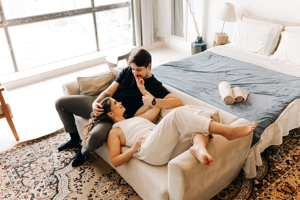 casal no sofá na frente da cama no apartamento