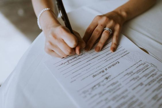 Mãos da noiva assinando certidão de casamento
