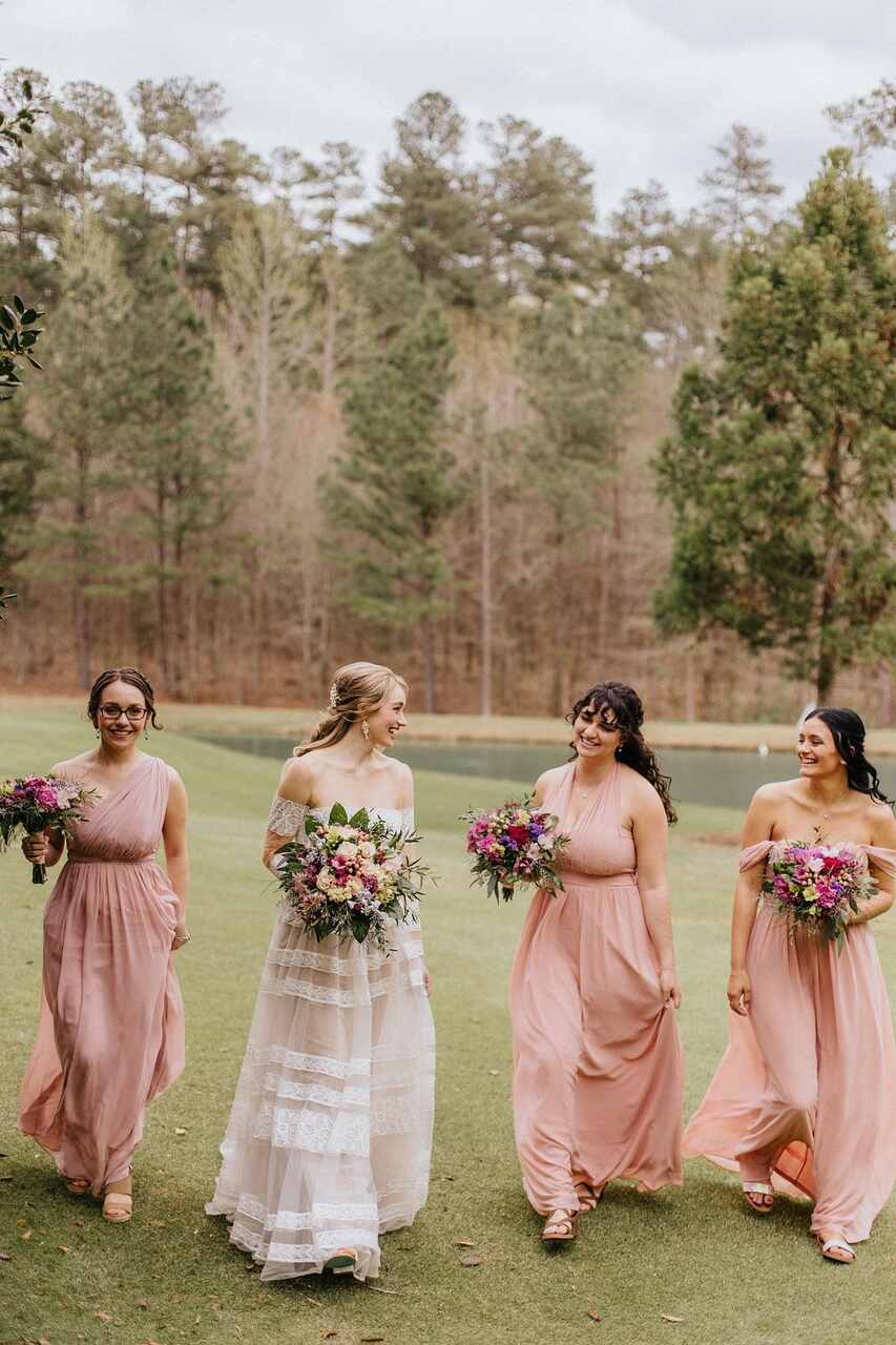 madrinhas com vestido rosa segurando buquê ao ar livre