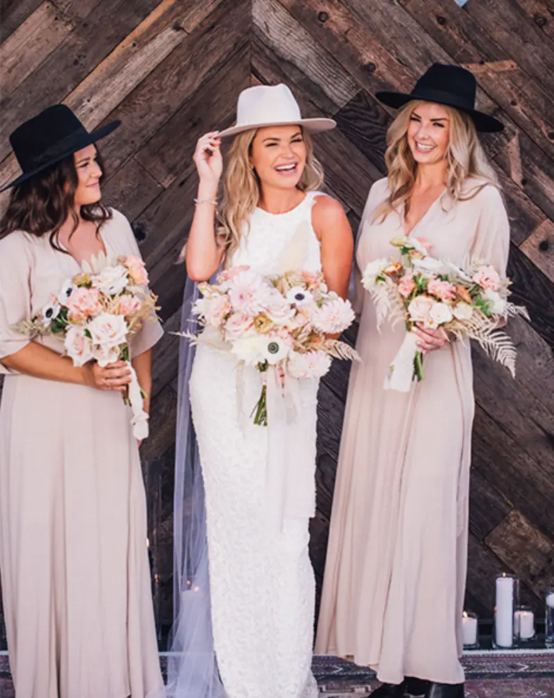 madrinhas usando chapéu e noiva ao lado em frente a porta de celeiro
