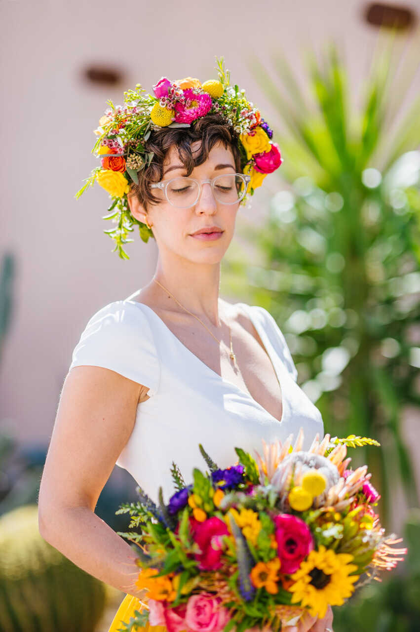 Noiva com coroa de flores no cabelo e um buquê com as mesmas flores coloridas do buquê