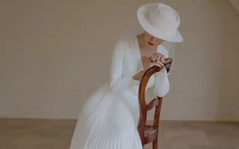 noiva de chapéu para casamento no campo sentada em uma cadeira