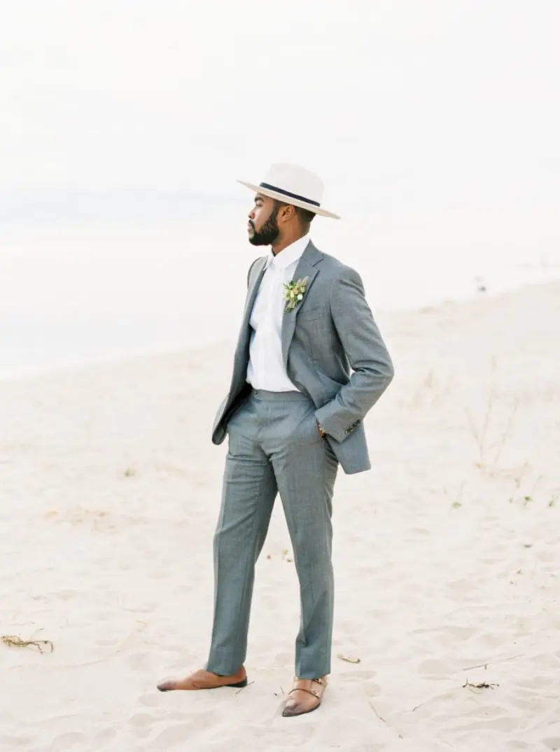 noivo de terno cinza e chapéu na praia