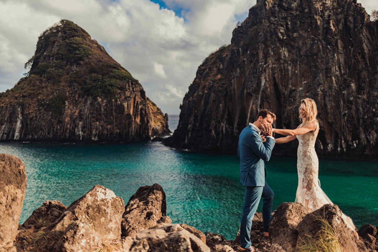 casal nas pedras de Fernando de Noronha com mar cristalino