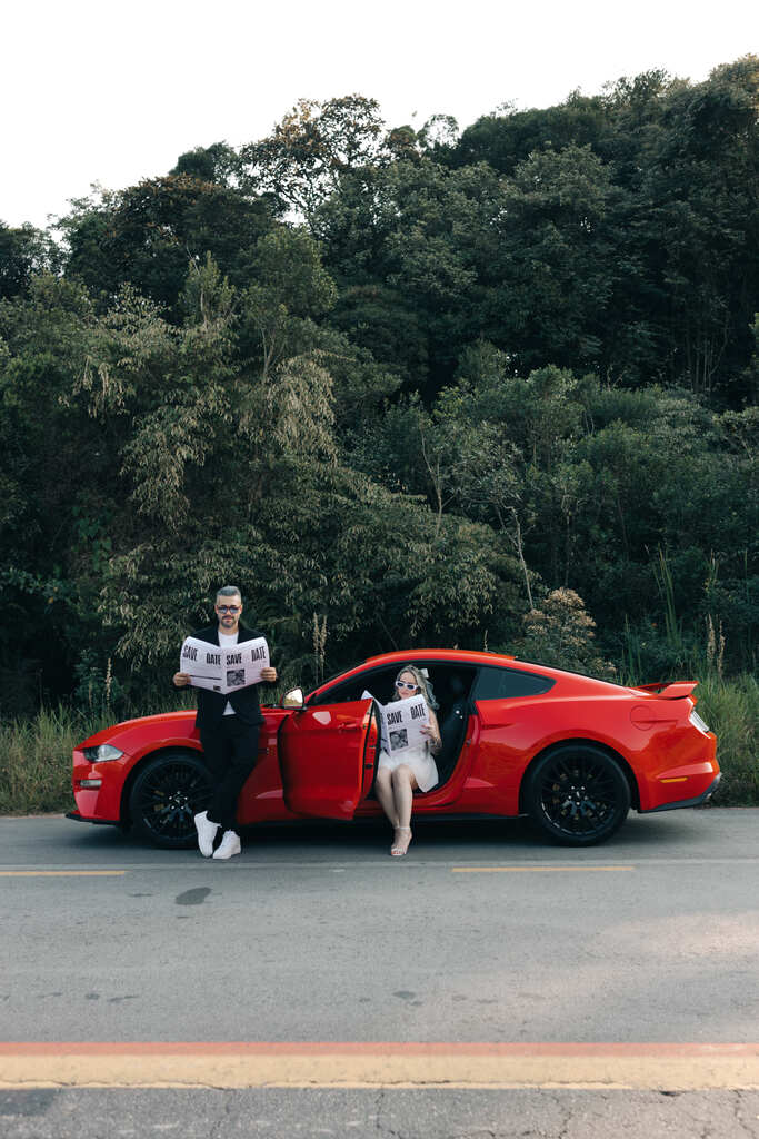 casal lendo jornal no carro esportivo vermelho