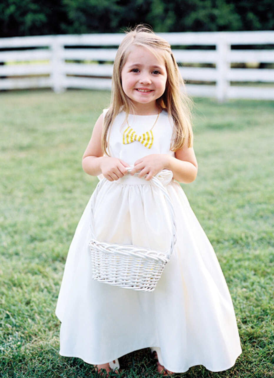 Daminha de honra de vestido branco e um colar amarelo e branco