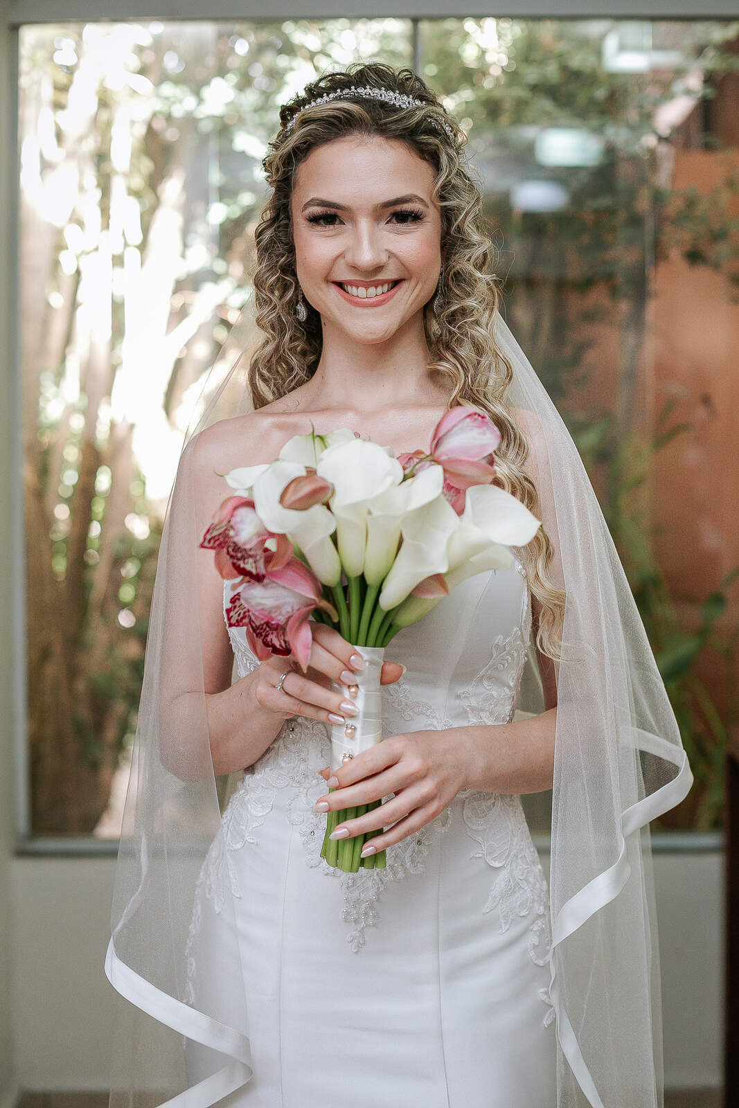 noiva com cabelo cacheado com buquê com flores brancas e rosas