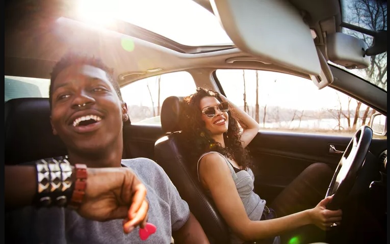 casal viajando de carro com teto solar aberto