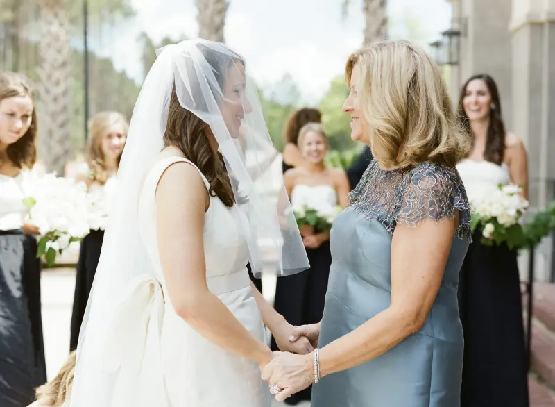 noiva de véu segurando a mão da sogra