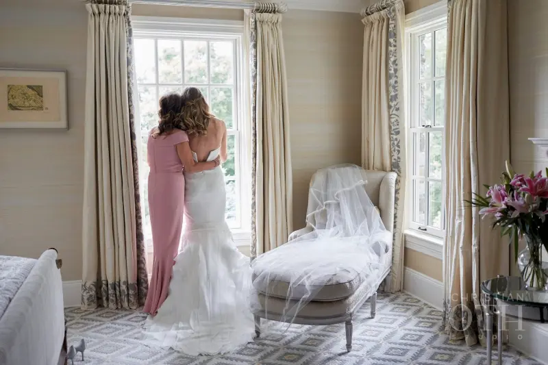 noiva e sogra se abraçando em frente a uma janela