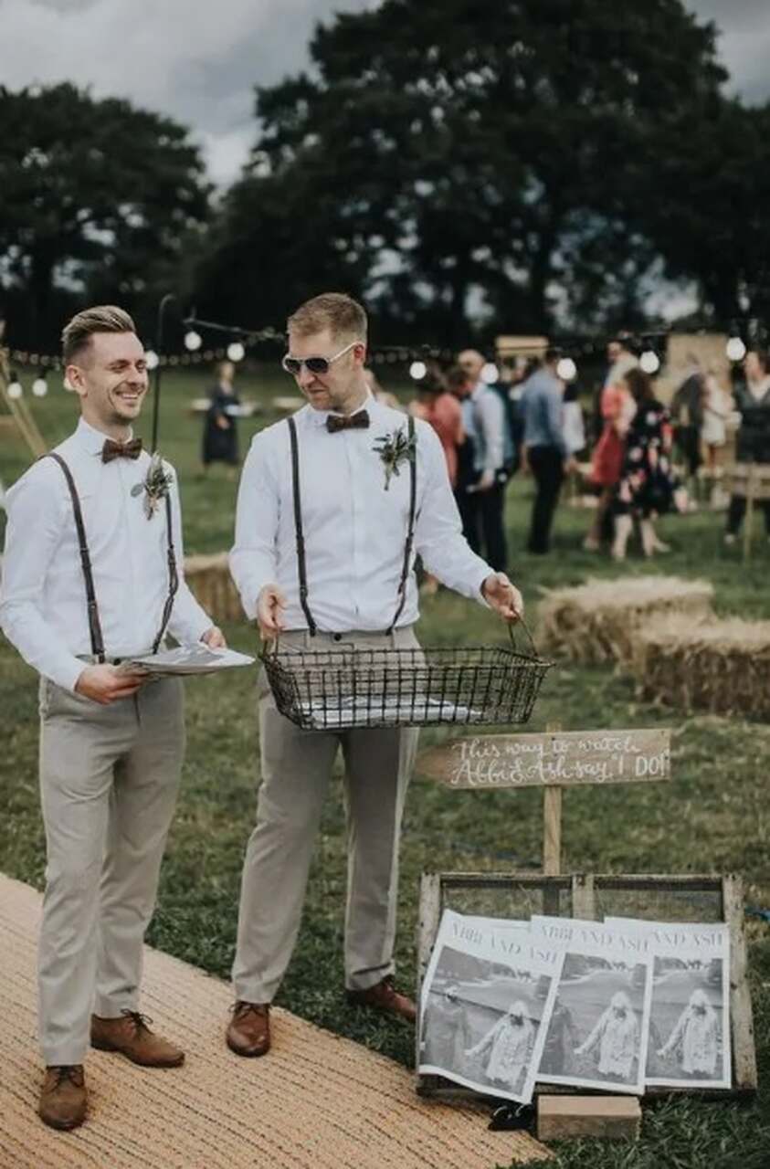 padrinhos de casamento com suspensório entregando jornal dos noivos