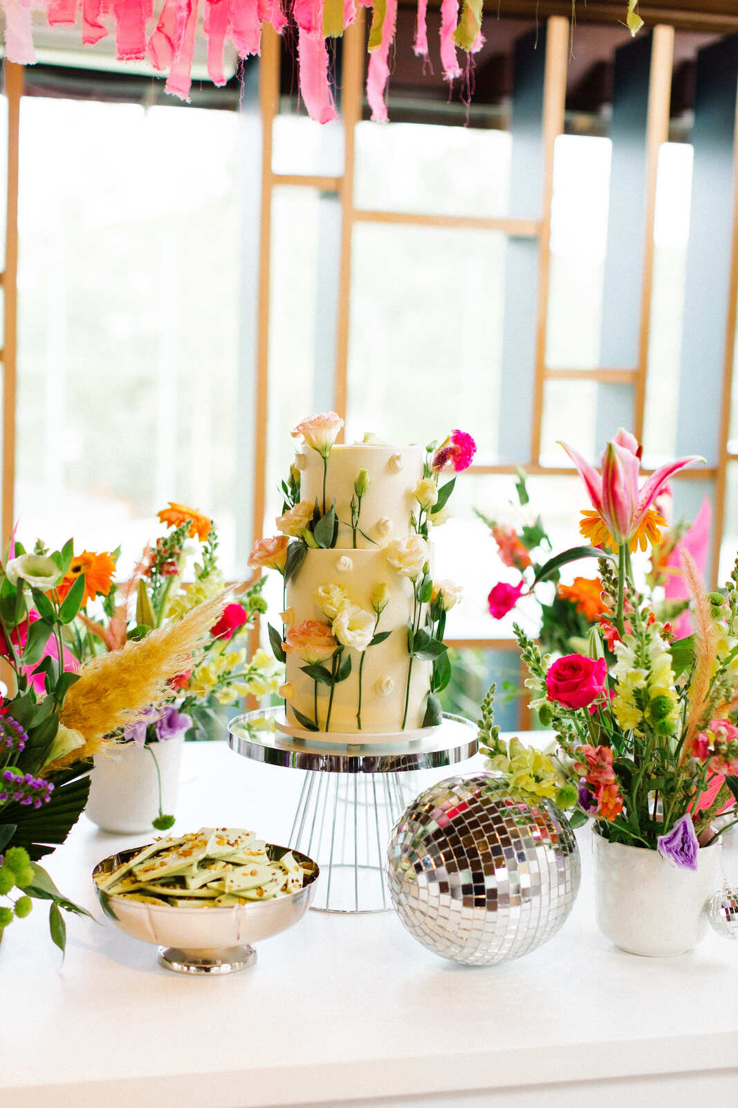 mesa com bolo de casamento e flores coloridas