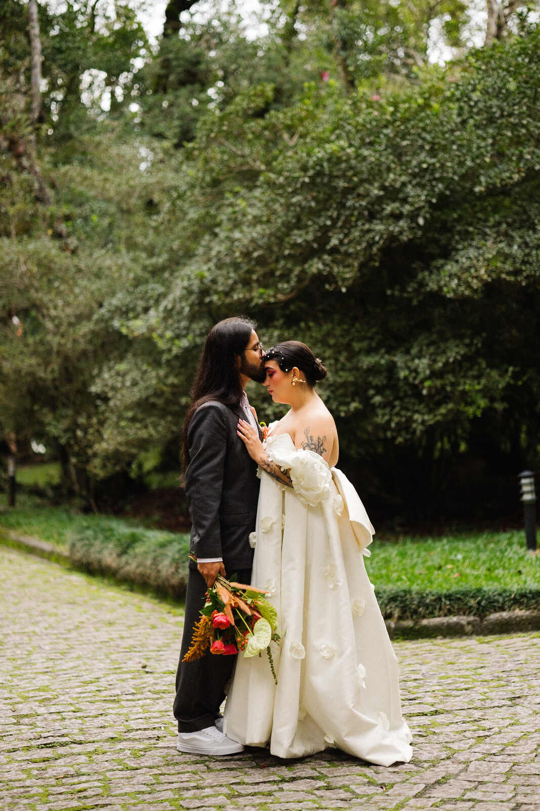 noivo segurando buquê beijando a testa da noiva