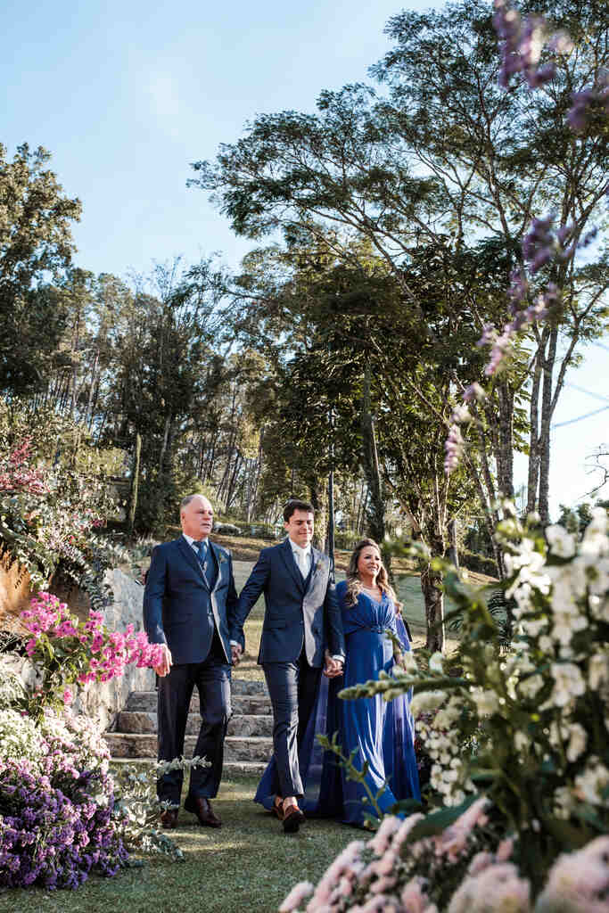 entrada do noivo com terno azul ao lado do pai e mãe