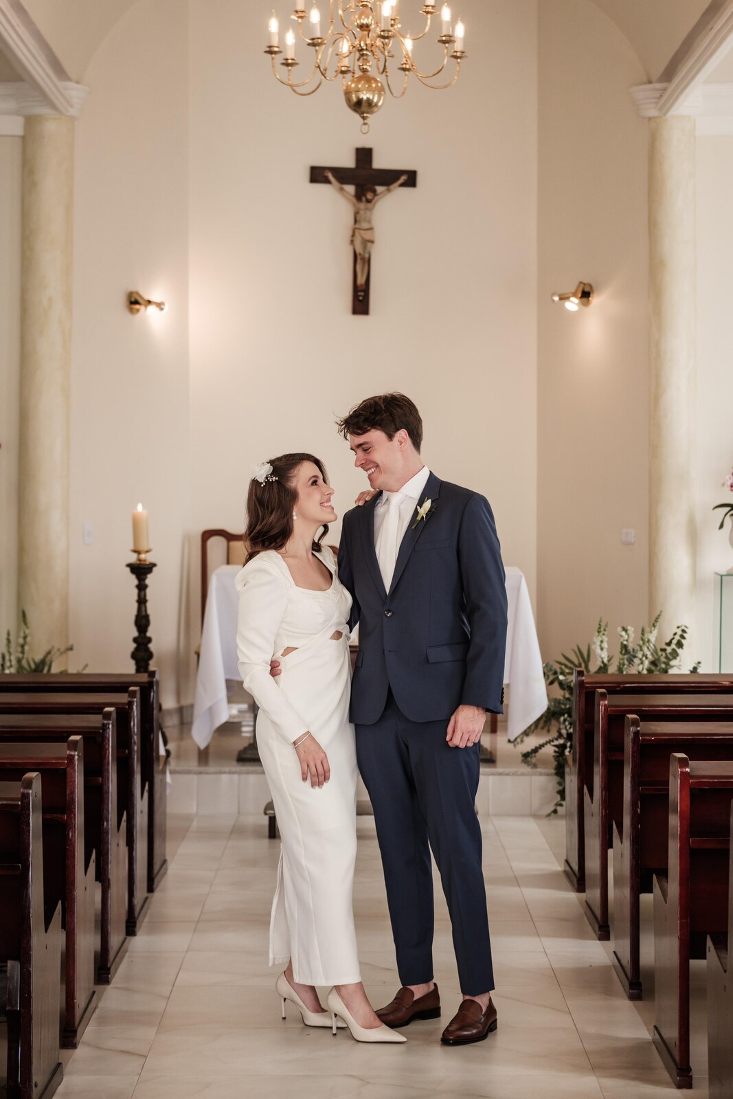 mulher com vestido de noiva modesto na igreja ao lado do noivo com terno azul escuro