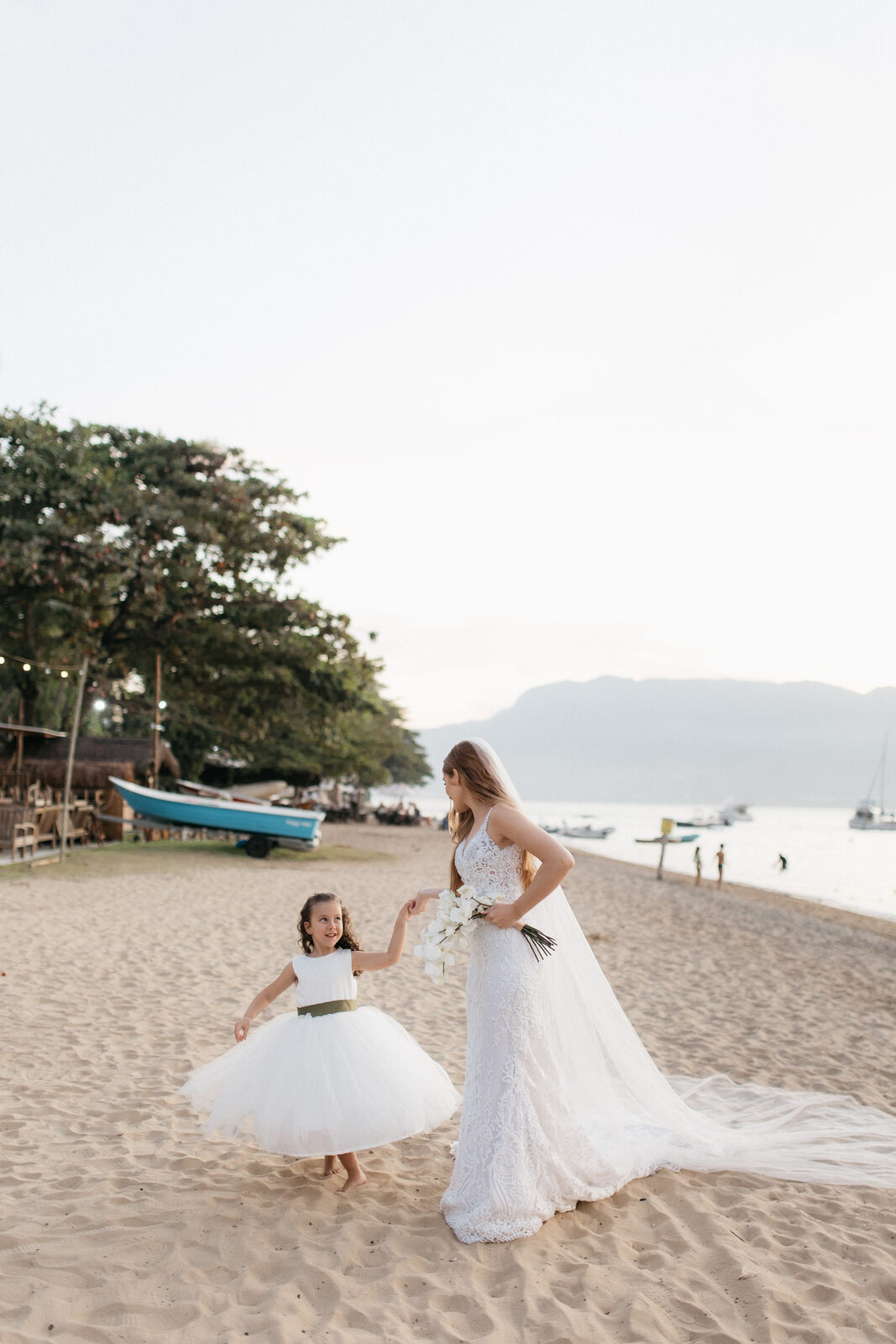 noiva de mãos dadas com daminha na praia