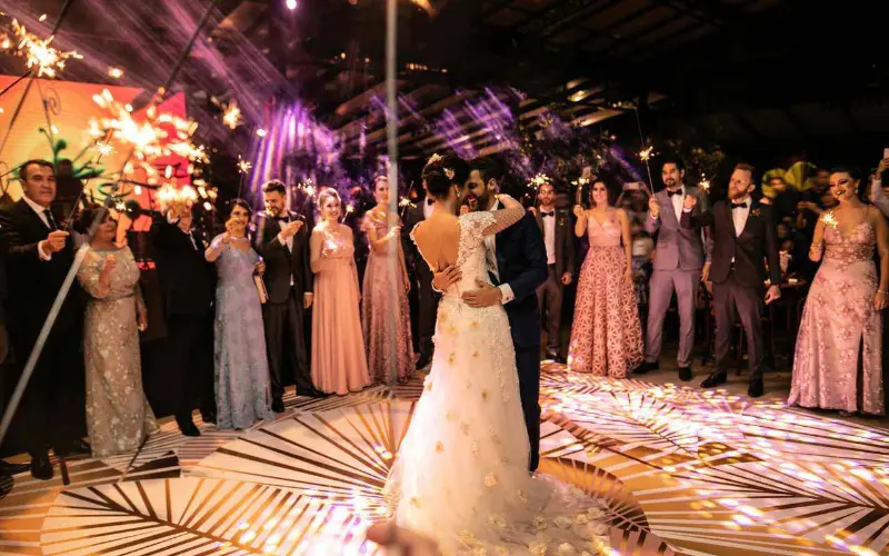 dan&ccedil;a dos noivos em casamento &agrave; noite com convidados ao redor