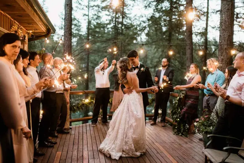 noivos dan&ccedil;ando no deck com convidados ao redor segurando sparkles 