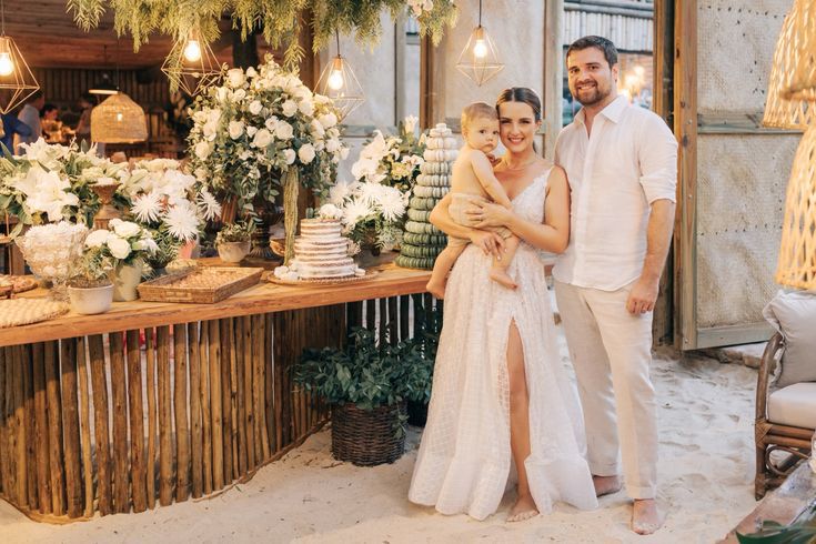 casal em frente a mesa do bolo com bebê