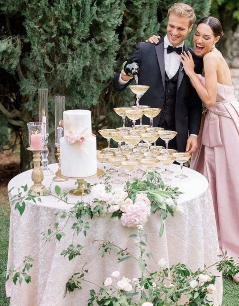 casal de noivos enchendo torre de taças em casamento estilo bolo e champanhe