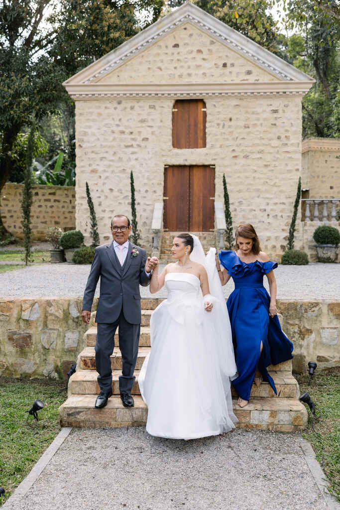 entrada da noiva com o pai com terno cinza e mãe com vestido azul