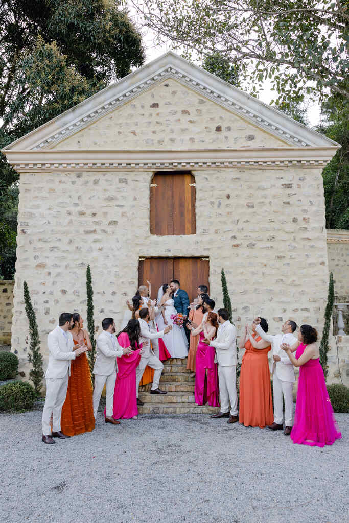 noivos padrinhos com roupa clara e madrinhas com vestidos rosa e laranja