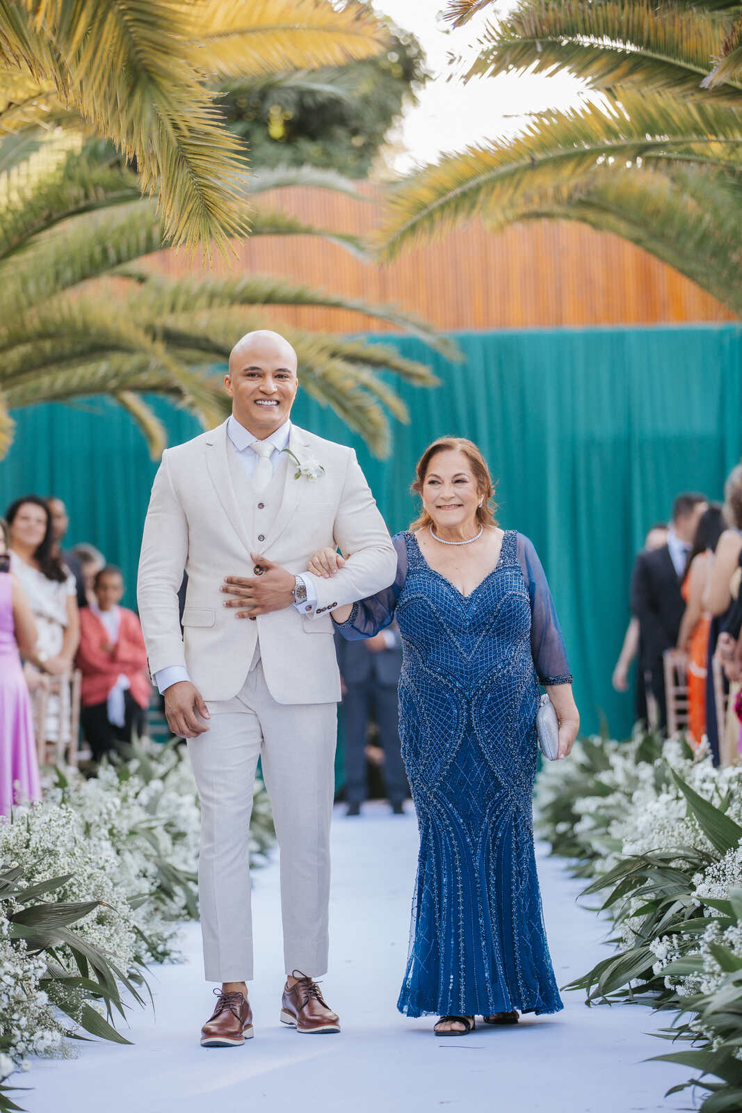 entrada do noivo ao lado da mãe com vestido azul escuro