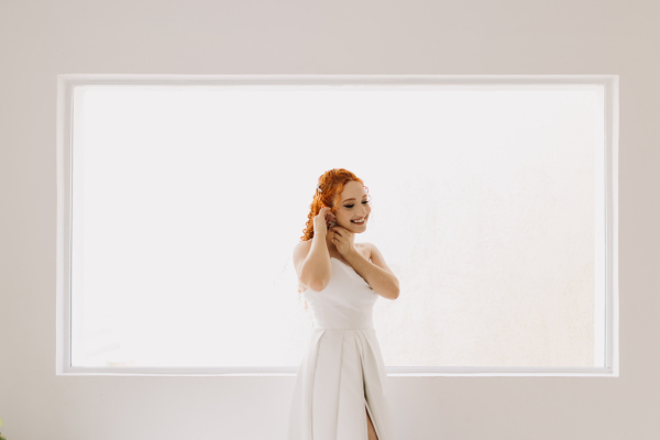 capa post: noiva ruiva colocando os brincos em um espaço branco