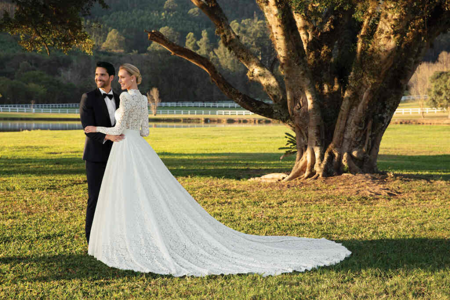 casal abraçados no campo, a noiva está com um vestido longo 