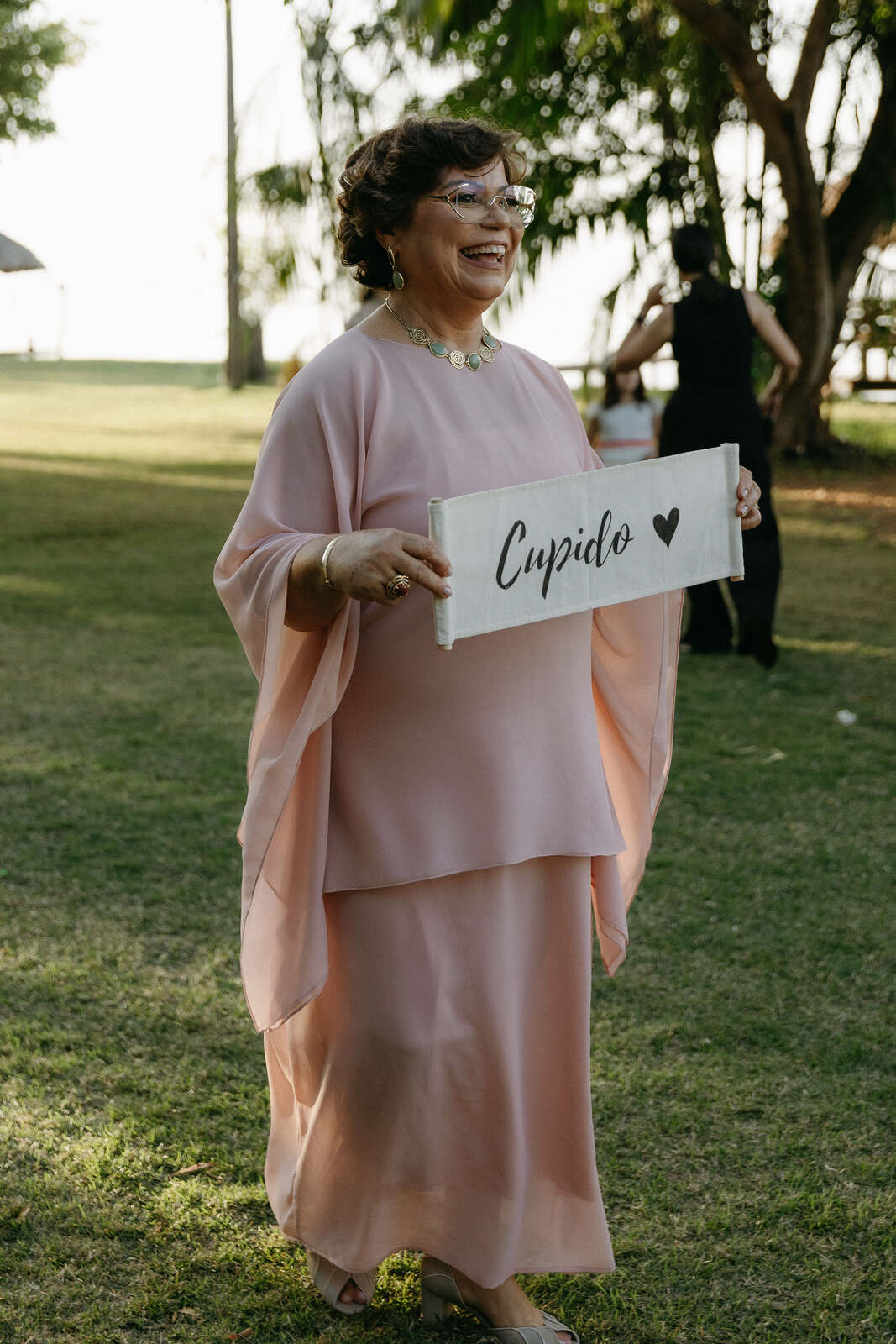 mulher de vestido salmão com plaquinha escrito cupido