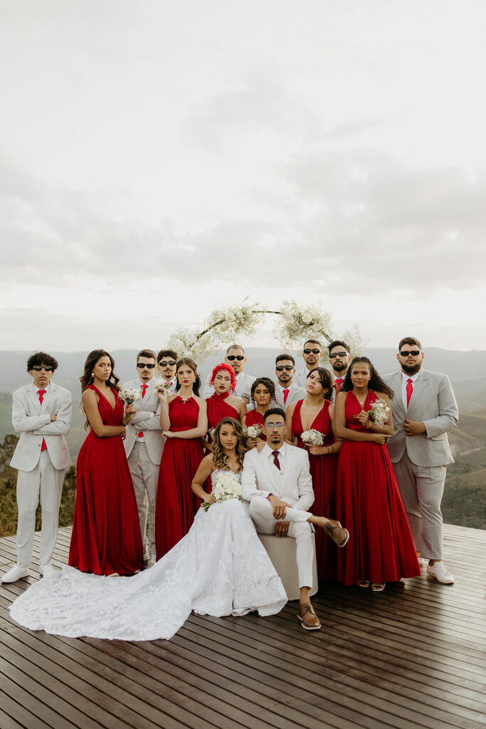 noivos ao lado das madrinhas de vermelho e padrinhos de terno cinza