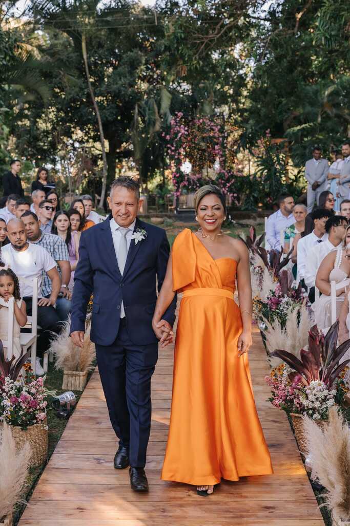 entrada do pai da noiva com terno azul e mãe com vestido laranja