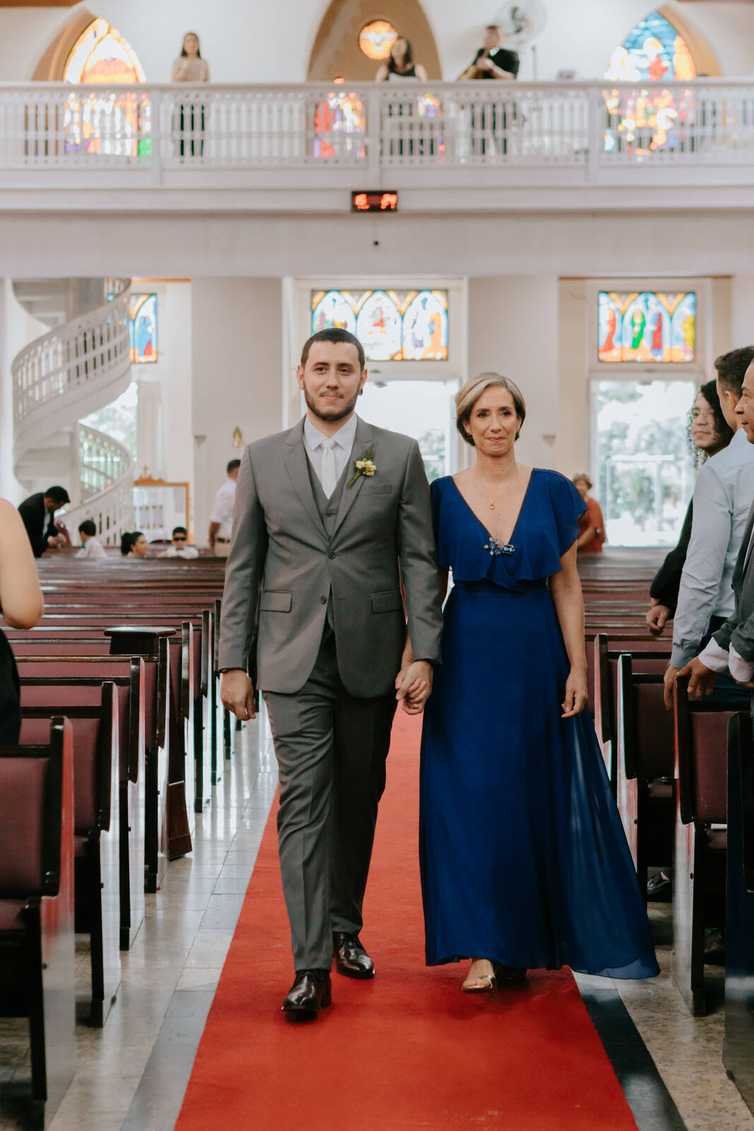 entrada do noivo com terno cinza e mãe com vestido azul cobalto