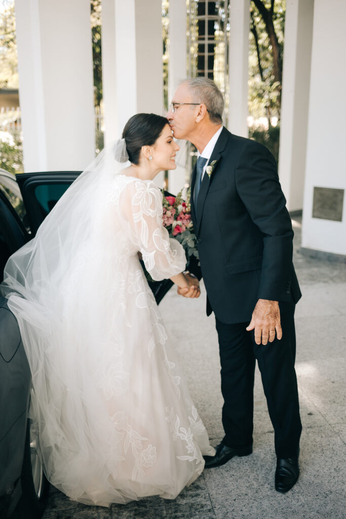 pai da noiva com terno preto beijando a testa da noiva