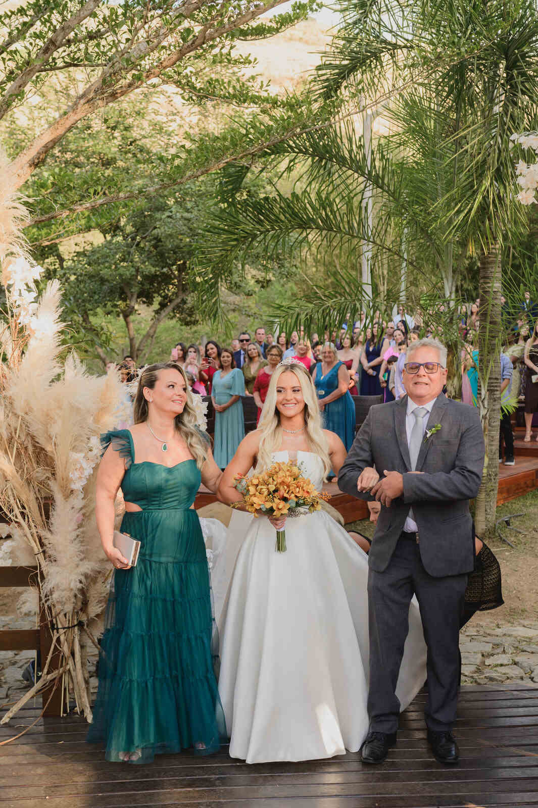 entrada da noiva com pai de terno cinza e mãe com vestido verde