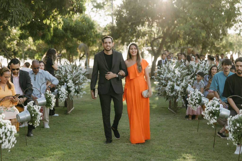 entrada do padrinho com terno preto e madrinha com vestido laranja