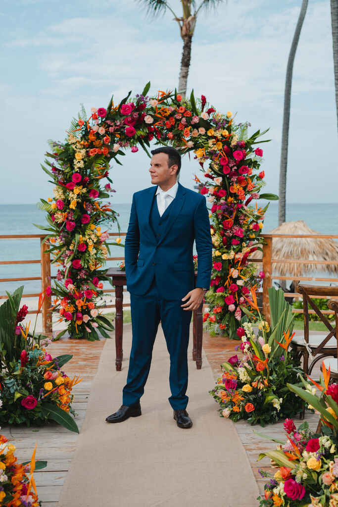 noivo com terno azul marinho no altar com decoração tropical