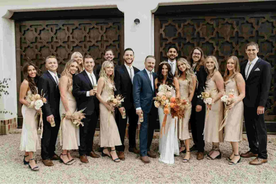 noivos com padrinhos e madrinhas posando para foto de casamento em frente a uma porta grande