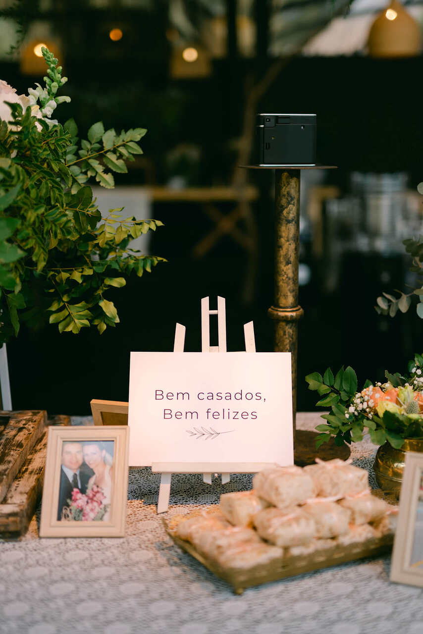 Pequena placa em cima de uma cavalete sobre a mesa, escrita Bem casados, bem felizes