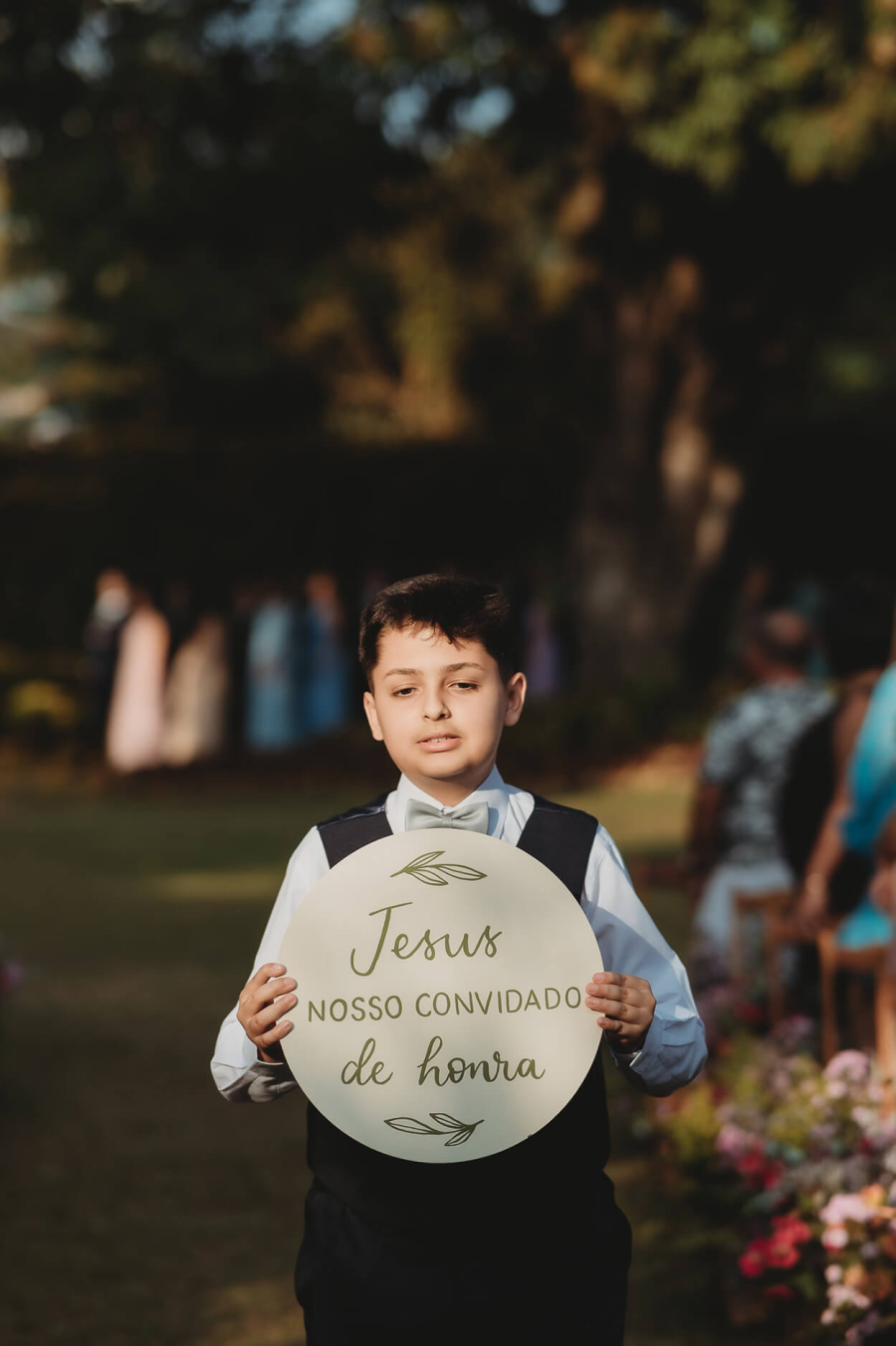 Pajem segurando uma placa redonda escrita: Jesus nosso convidado