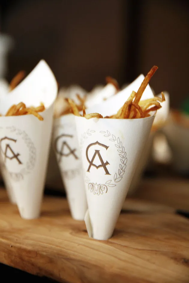 Batatas fritas servidas em cones personalizados com o monograma dos noivos