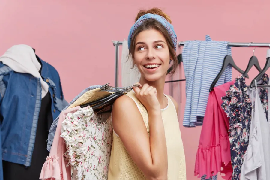 mulher feliz segurando roupas no cabide para vender dicas e arrecadar dinheiro para casamento