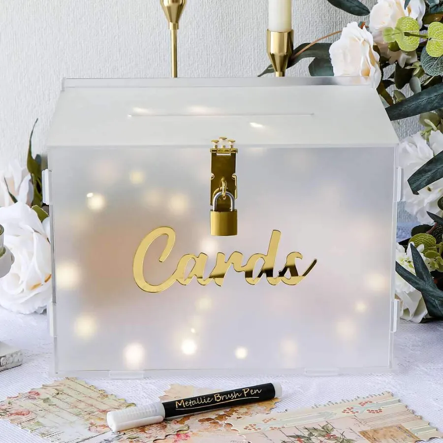 caixa semi transparente com cadeado e escrito cards em dourado para arrecadar dinheiro para casamento