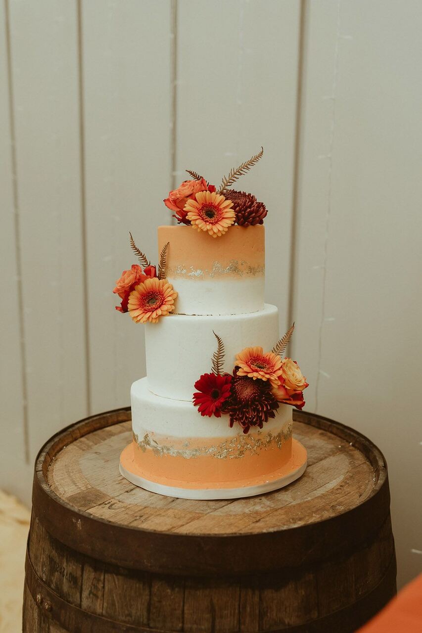 Bolo de três andares branco com laranja e flores laranjas e marsala