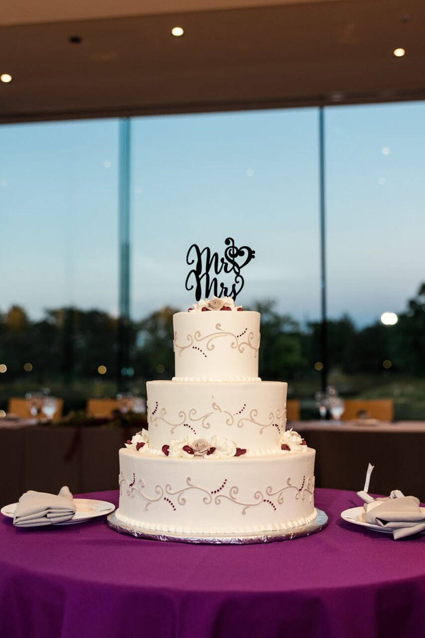 Bolo branco de 3 andares com detalhes em arabesco roxo e topo do bolo escrito Mr e Mrs