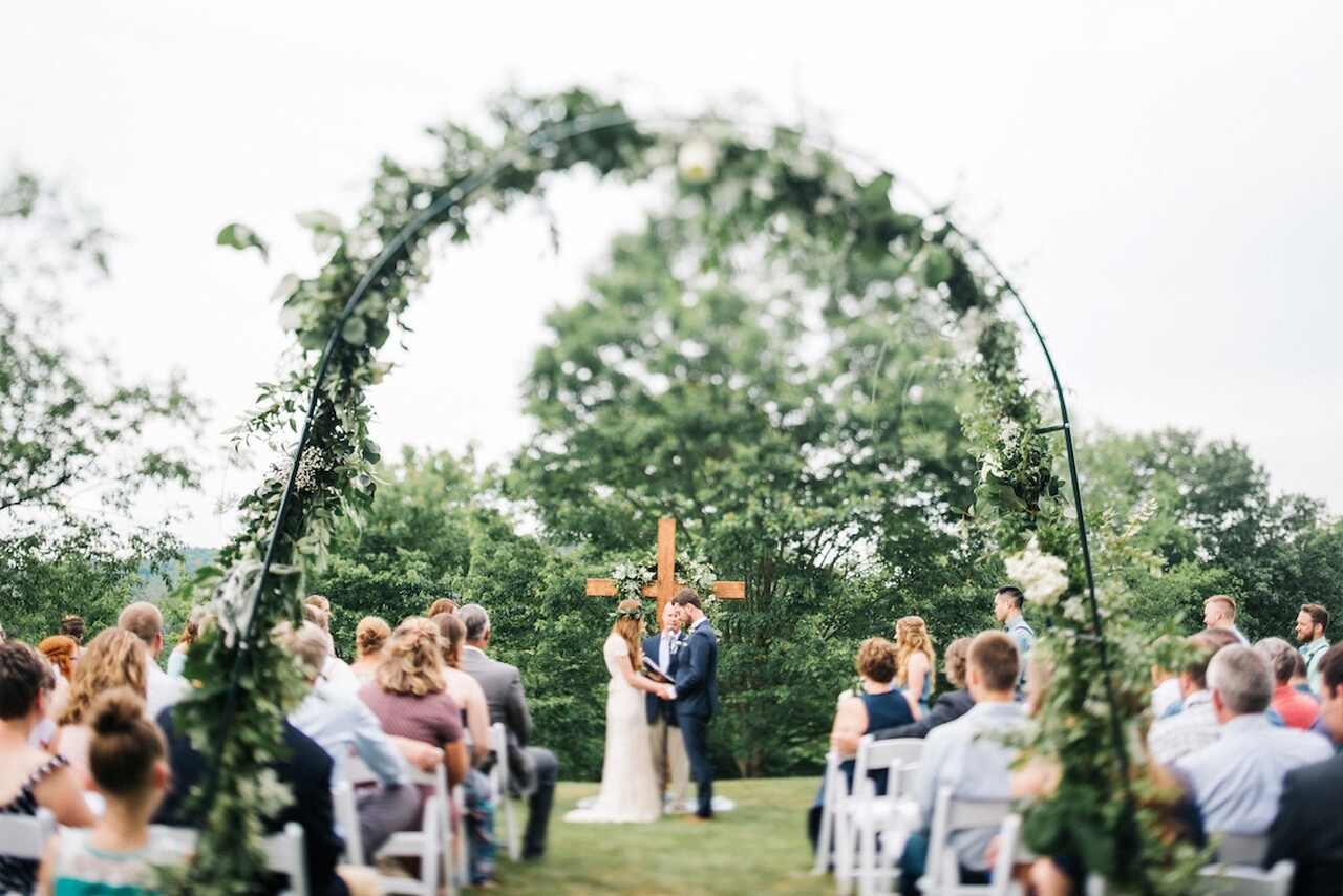 Cerimônia de casamento ao ar livre. Casal no altar com o pastor. Um cruz de madeira ao fundo