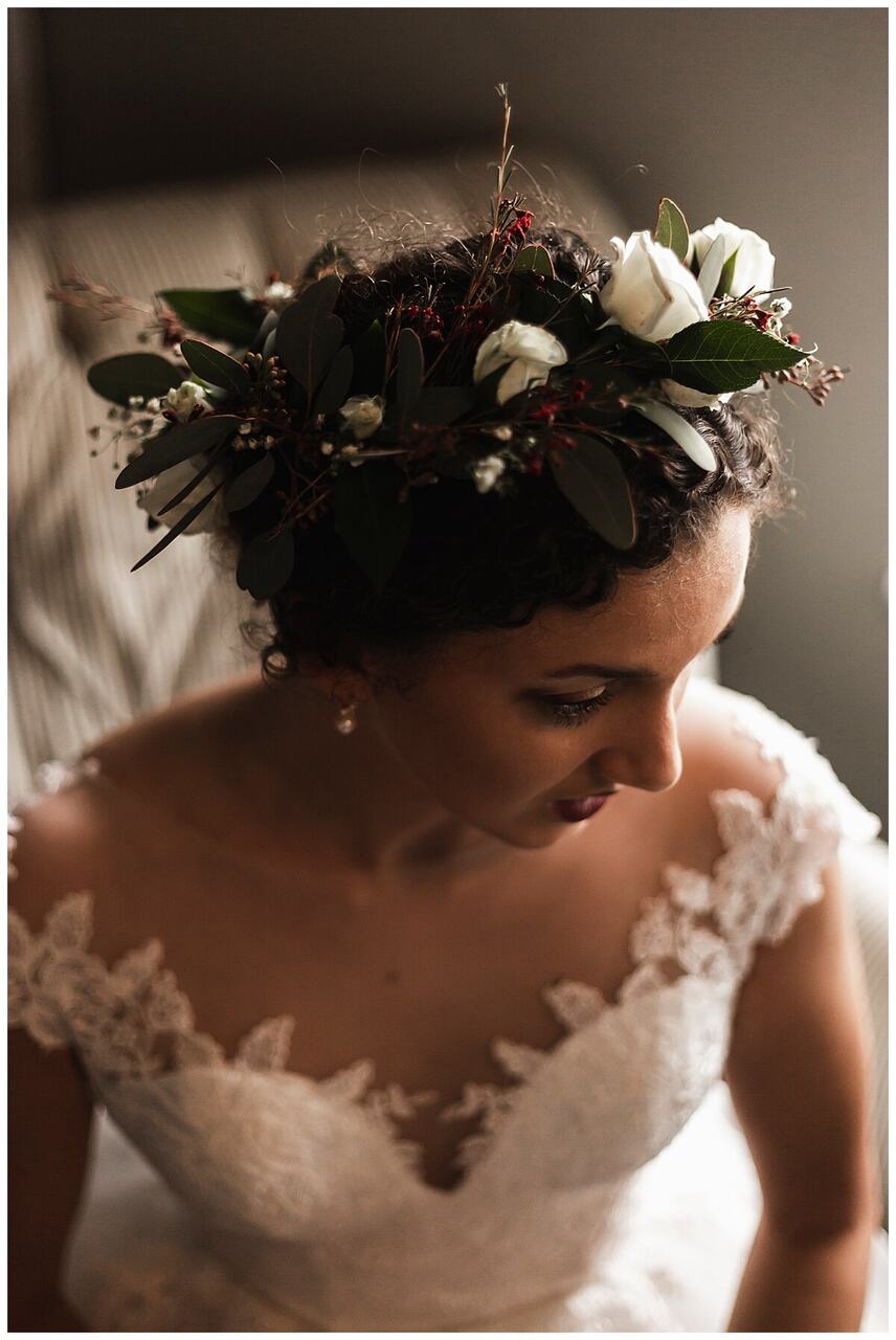 Noiva olhando para baixo. Foco na coroa de floras e folhas em sua cabeça